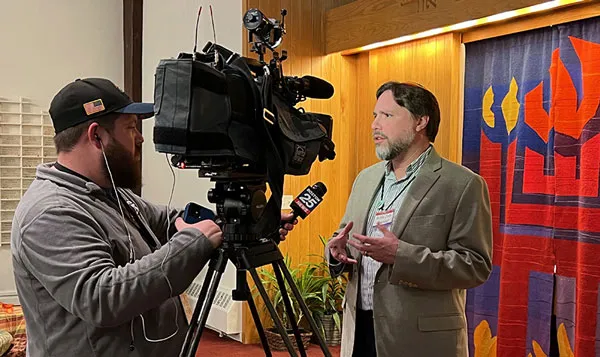 Rabbi Josh speaking to the media, being filmed by a camera operator